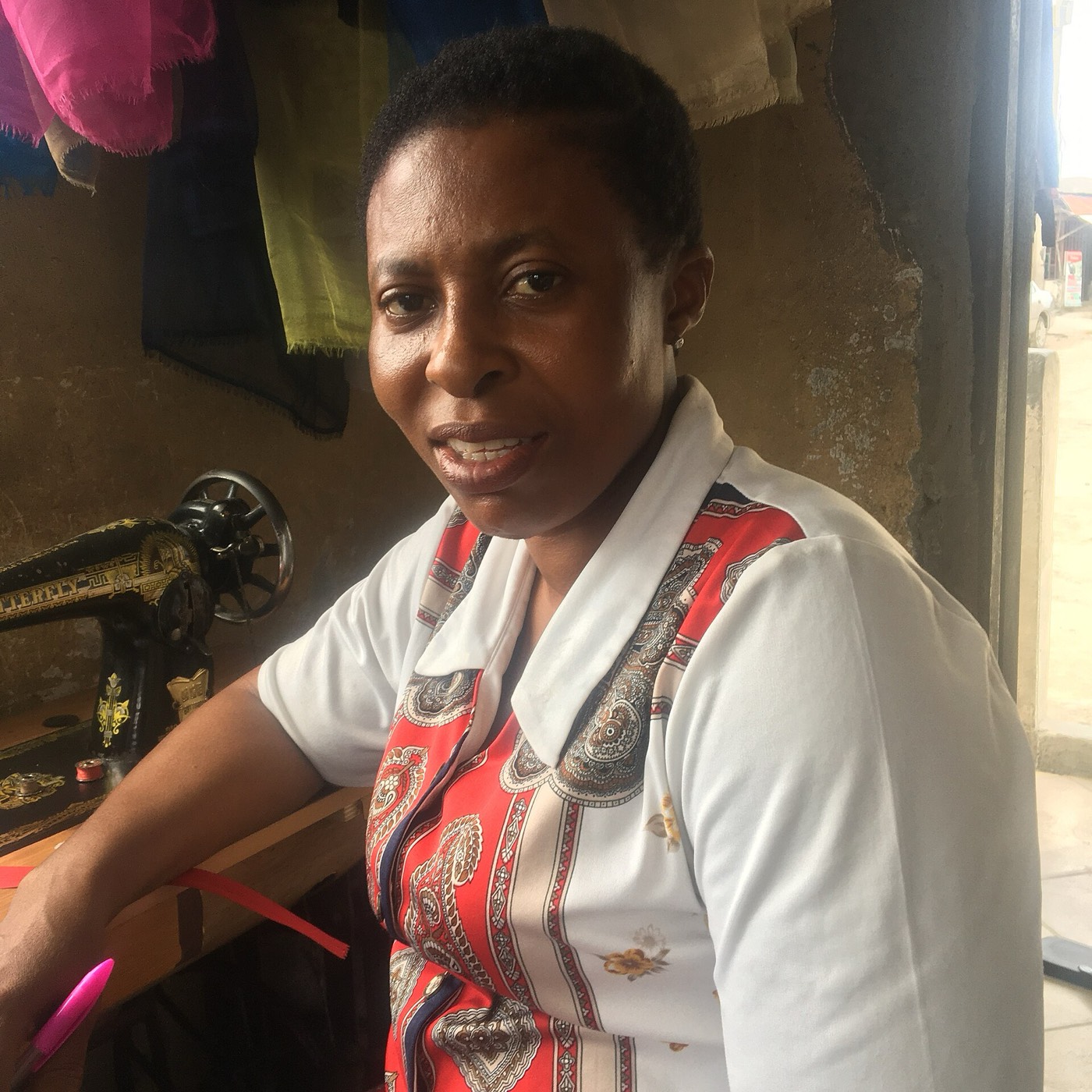 A tailor smiling beside her sewing machine