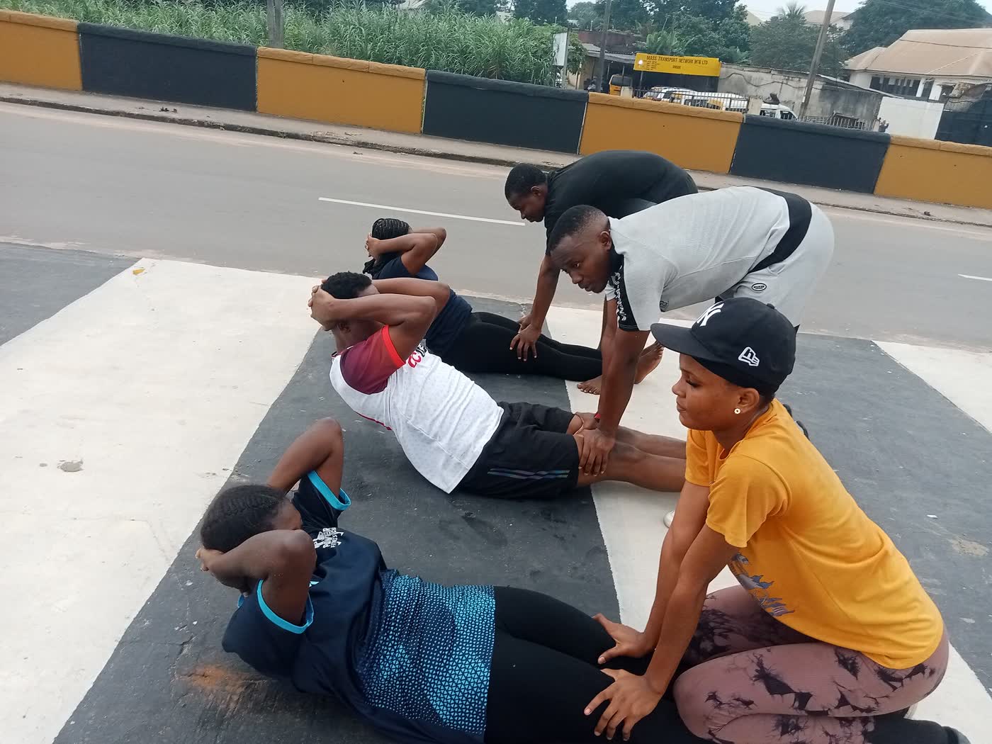A group doing sit-ups on a road during a community fitness walk in Imo State