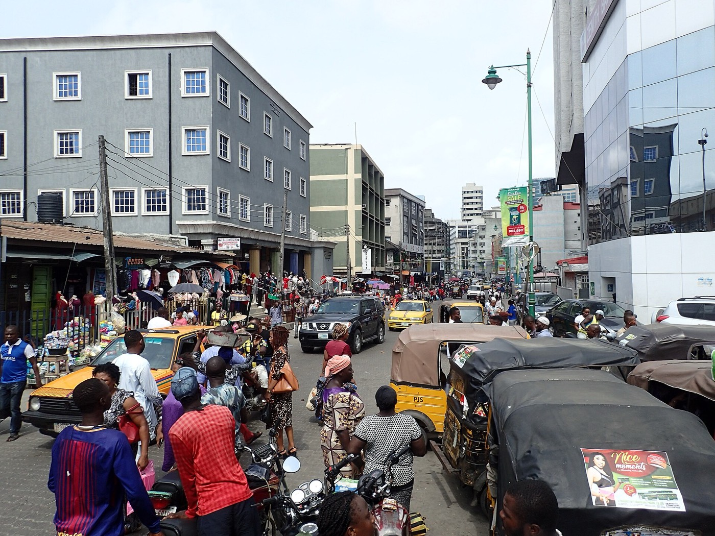 A busy shopping street in Lagos with shops and traffic